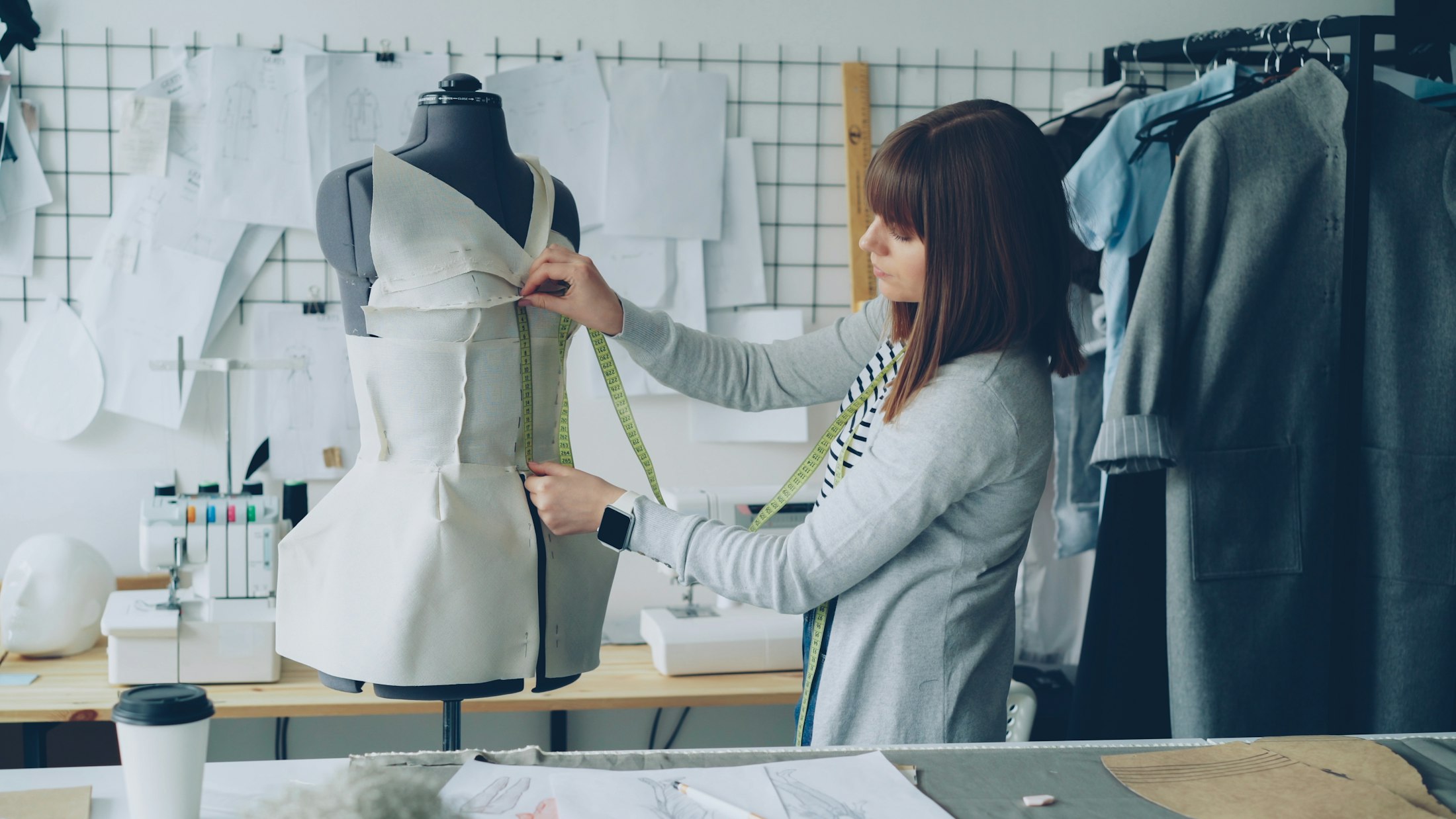 Eine Frau misst im Atelier ein Kleidungsstück an der Schneiderbüste — Beispielbild
